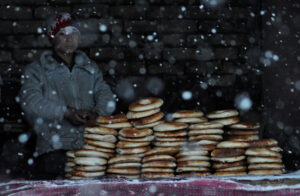 An afghan baker waits for customers behind a pile of breads during a snowy day in Mazar-e-sharif, Afghanistan. December 27th 2012.